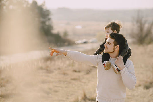 A child on a parent's shoulders pointing at the horizon