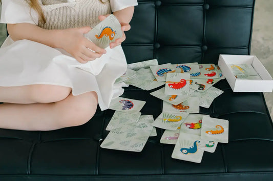 A little girl playing an animal matching card game on a sofa